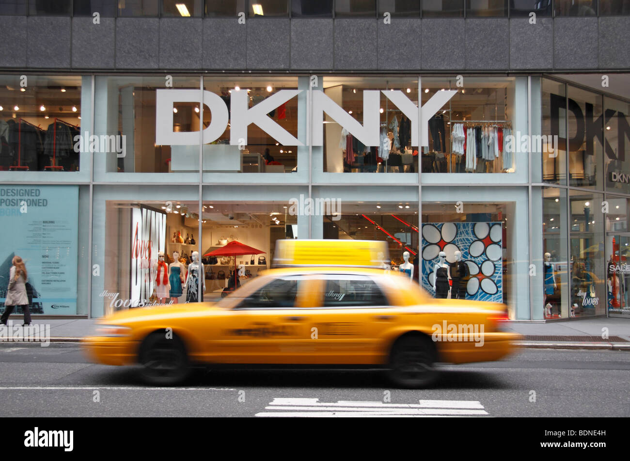Un giallo New York taxi passando davanti al DKNY negozio di moda, Madison Avenue, New York, Stati Uniti. Foto Stock