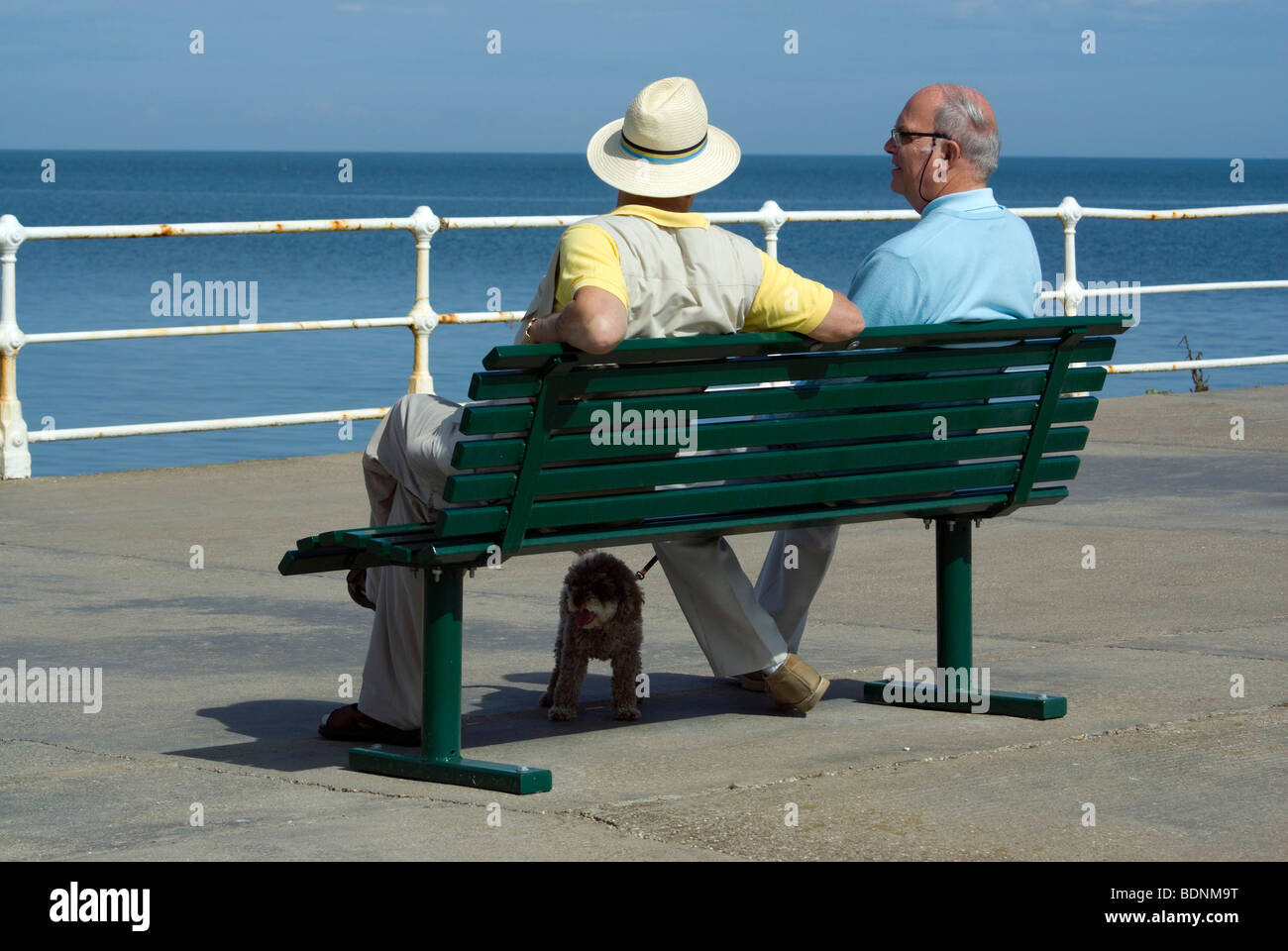 Due ben vestito anziani signori chattare su una sede sul molo di Whitby, Yorkshire. Foto Stock