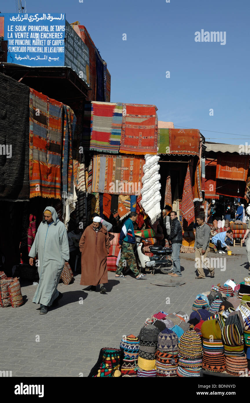 Marocchino arabo musulmano uomini che indossano Jellabas nel tappeto Bazaar, mercato o souk, Marrakech, Marocco Foto Stock