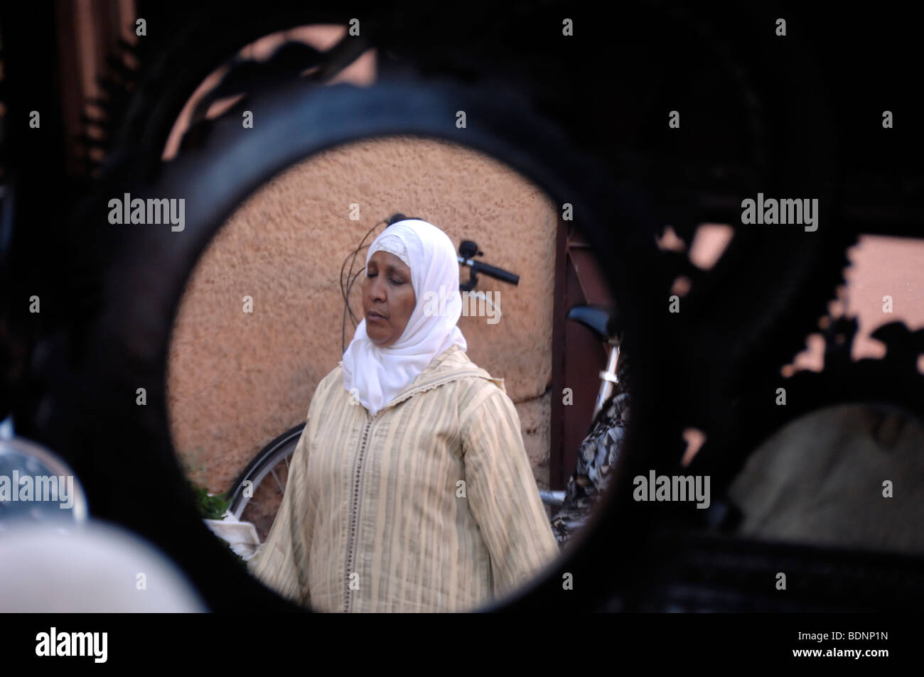 Donna musulmana marocchina che indossa una sciarpa islamica, un velo o un hijab riflesso in Mirror of Market Stall, Marrakech, Marocco Foto Stock