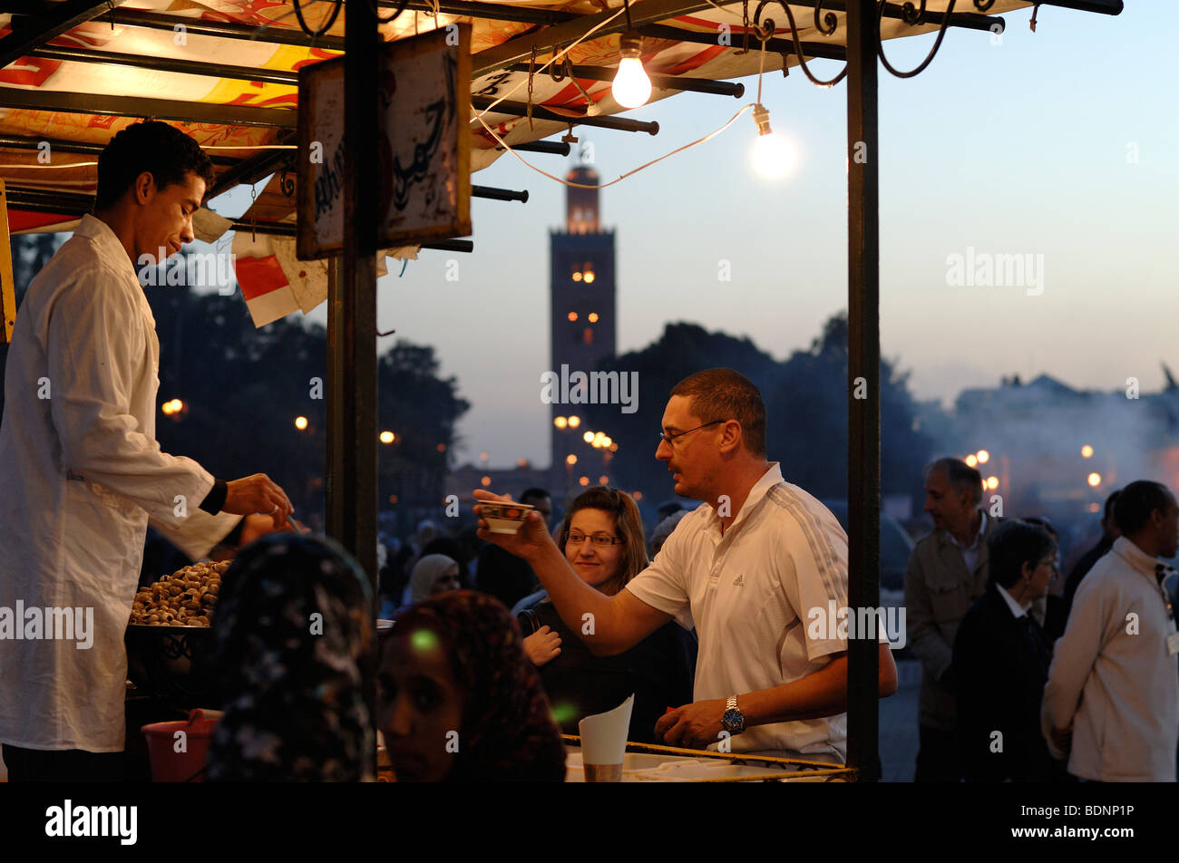 Pressione di stallo di Cibo & Turisti acquistare bevande al crepuscolo in Djemaa El-Fná o Djemaa El Fna, Marrakech, Marocco Foto Stock