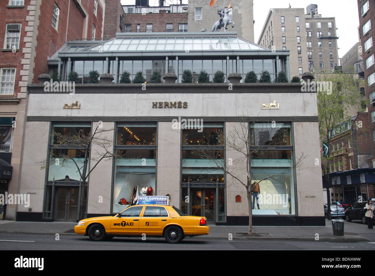 Un giallo New York taixi cabina passando la Hermes fashion store di Madison Avenue a New York City, Stati Uniti. Foto Stock