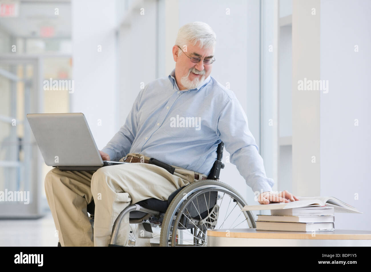 Professore universitario a leggere un libro e utilizzando un computer portatile Foto Stock