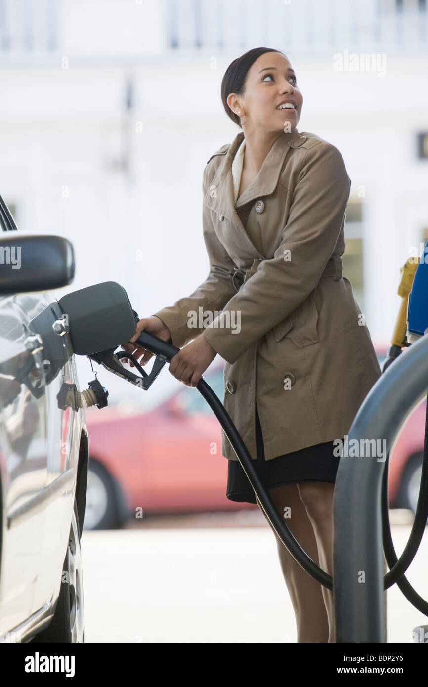 Donna ispanica il riempimento di un auto in una stazione di benzina Foto Stock