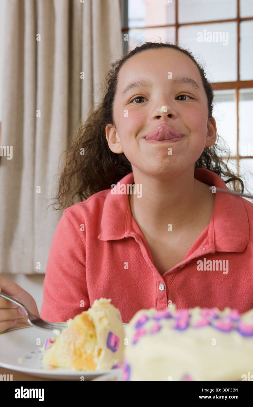 Ragazza cercando di leccare la torta ciliegina sul naso Foto Stock