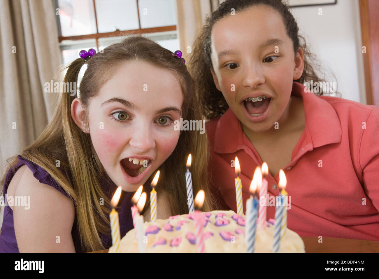 Due ragazze soffiando fuori candele su una torta di compleanno Foto Stock