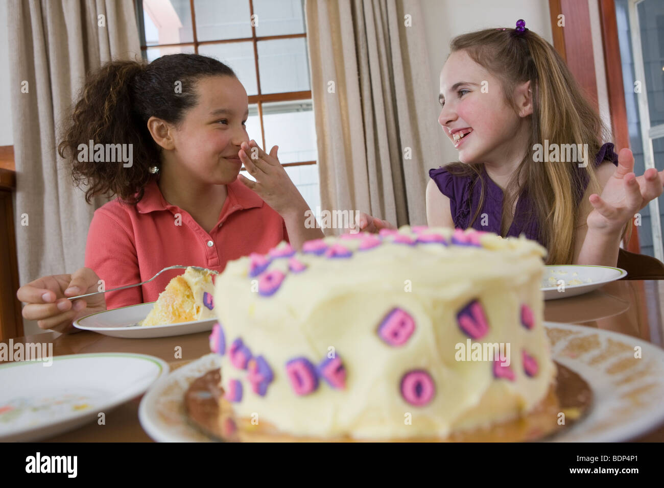 Due ragazze di mangiare la torta di compleanno e sorridente Foto Stock