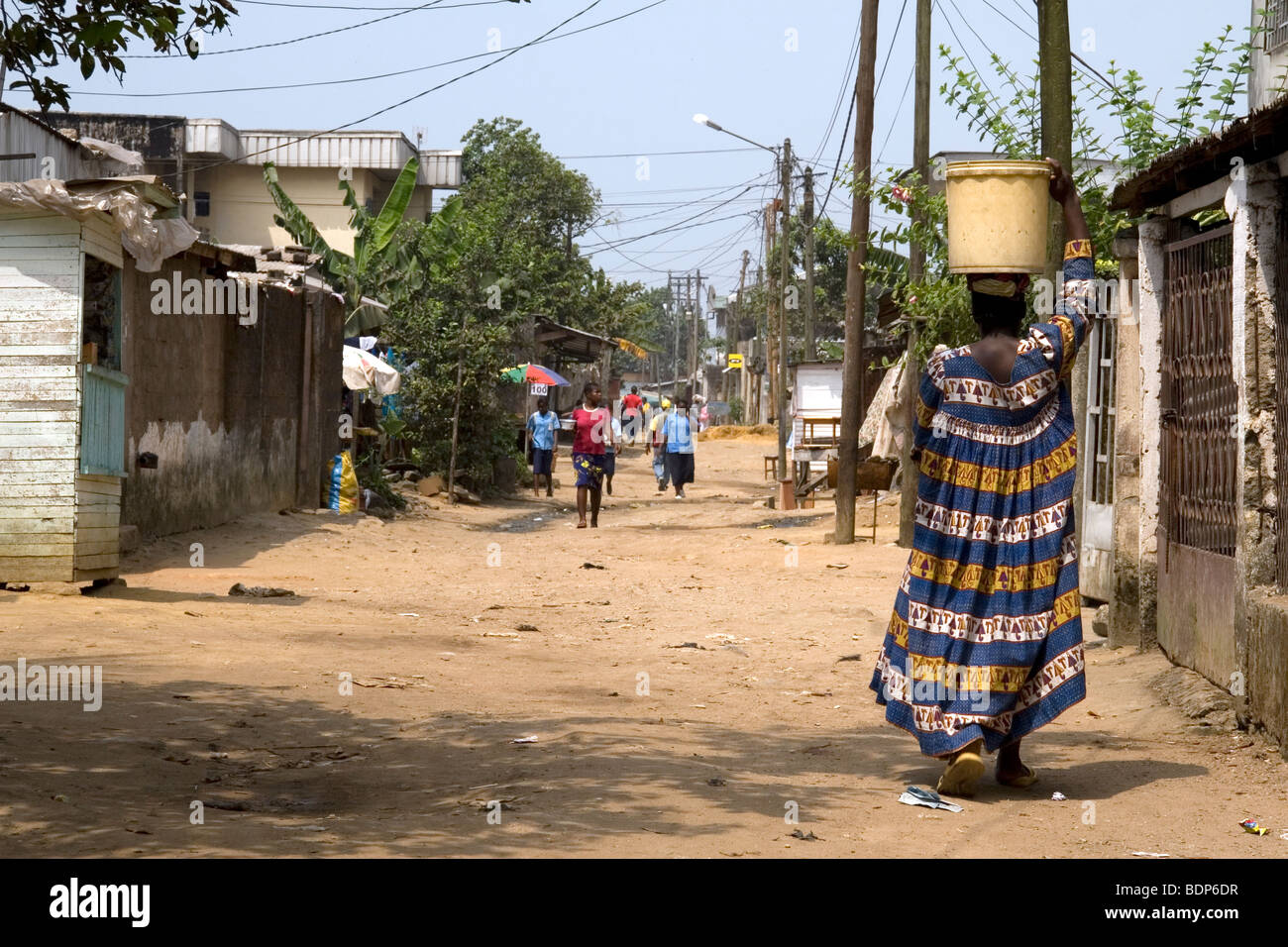 Donna che trasportano l'acqua sul suo capo nel quartiere povero di Grand Moulin Douala Camerun Africa occidentale Foto Stock