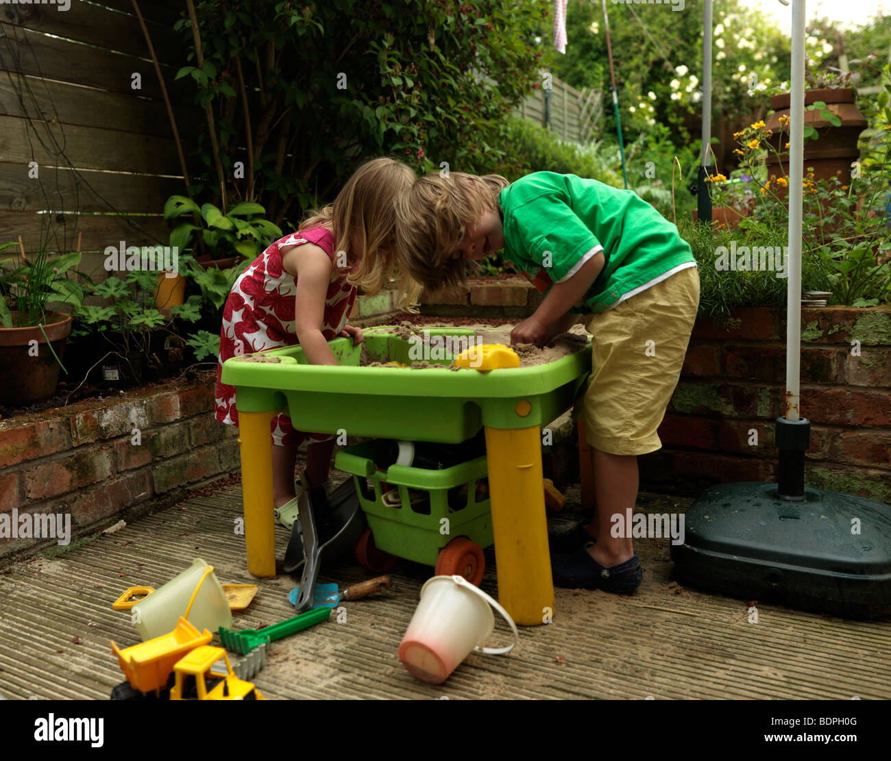 Fratello e Sorella gioca con la sabbia in giardino sul retro Birmingham West Midlands Foto Stock