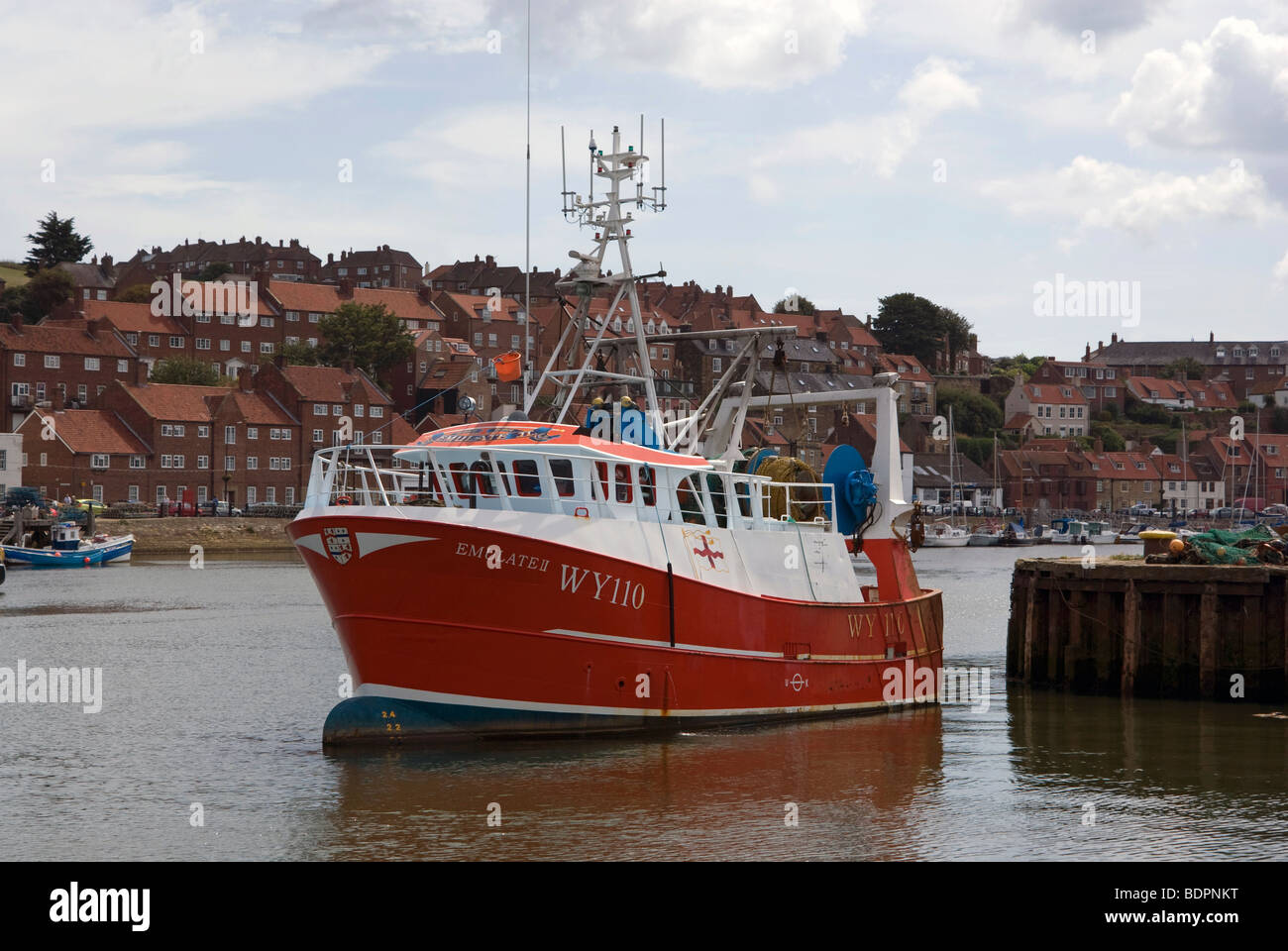 Un rosso barca da pesca di lasciare il porto di Whitby. Foto Stock