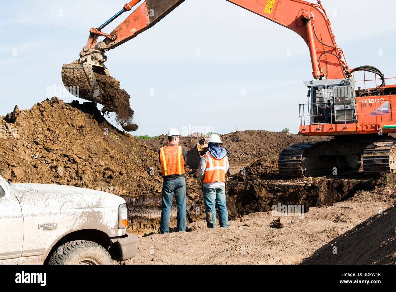 Lavoratori edili e escavatore a una pipeline sito in costruzione Foto Stock