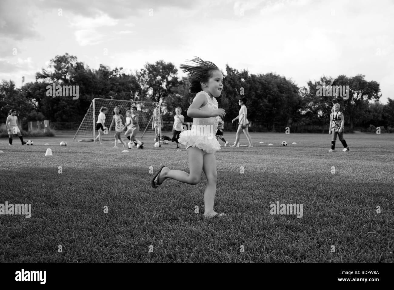 In bianco e nero del giovane ragazza in ballerina tutu in esecuzione sul campo di calcio Foto Stock