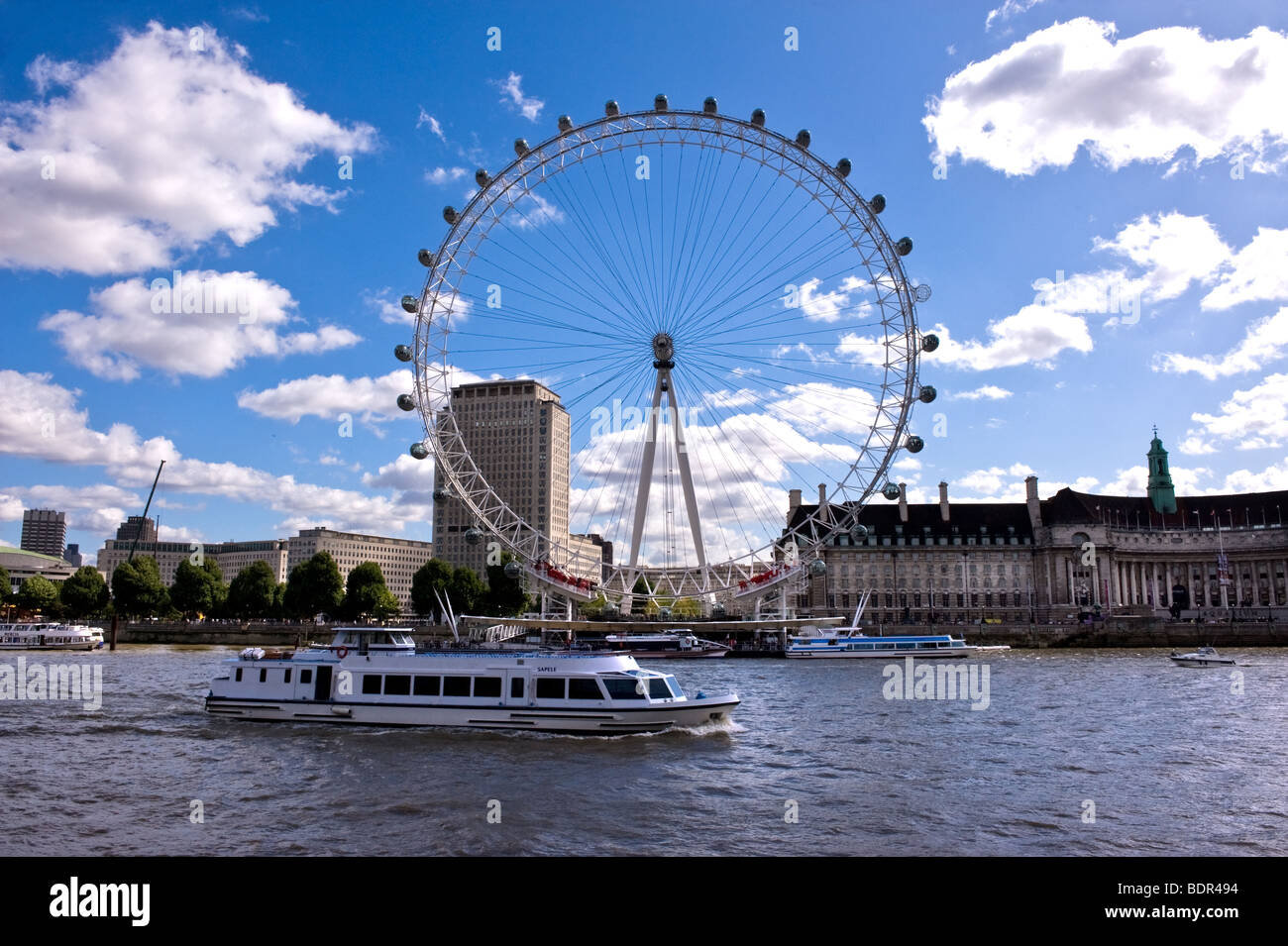 Una barca da diporto sul Tamigi che naviga oltre il London Eye. Foto Stock