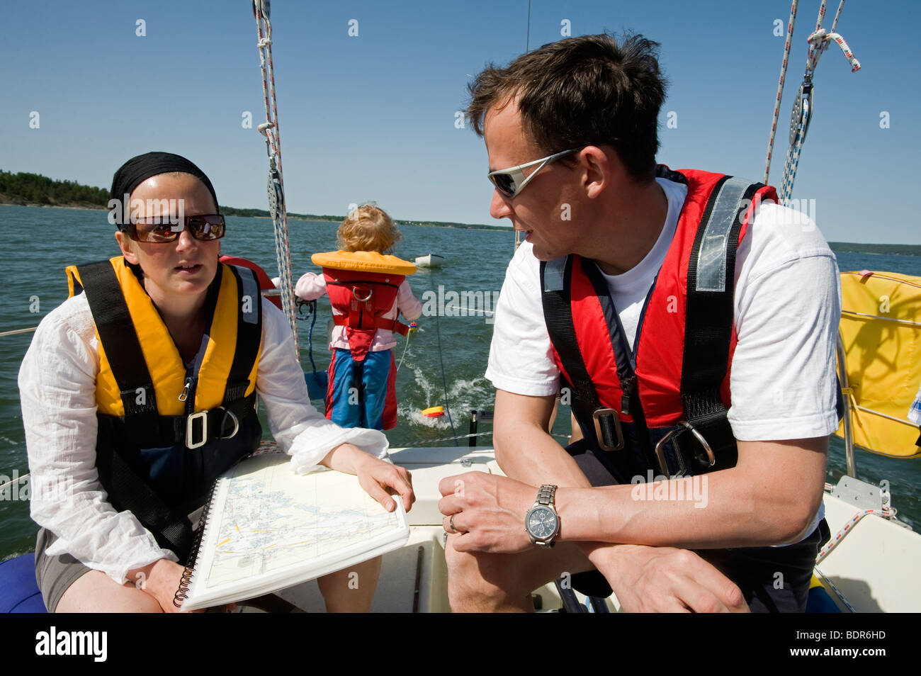 Un uomo e una donna che utilizza una marina nautico grafico su una barca a vela in Svezia. Foto Stock