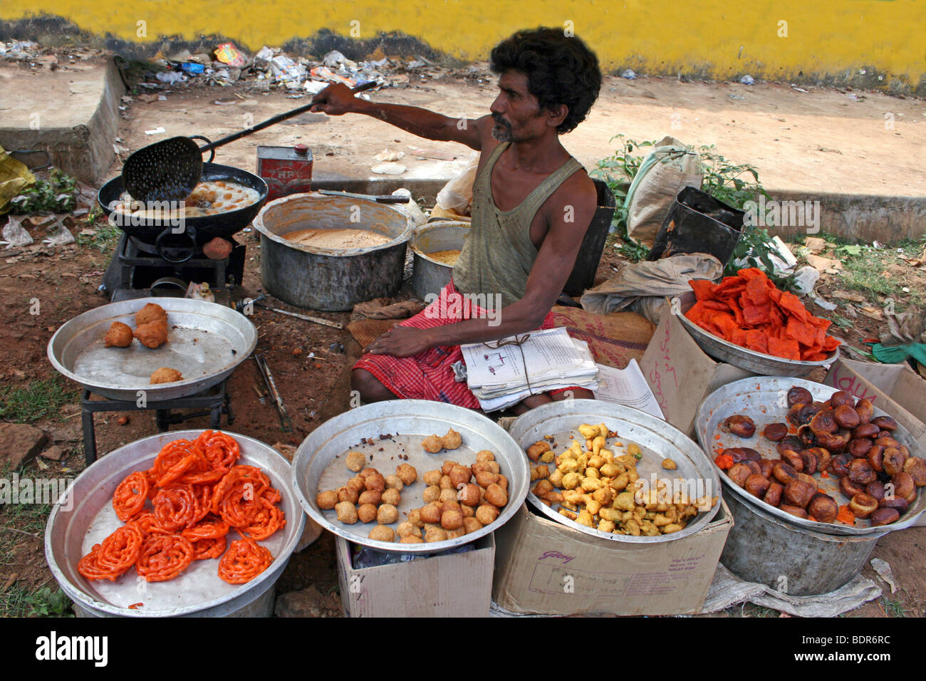 Uomo indiano Samosa di frittura e Doughballs In un mercato Orissan Foto Stock