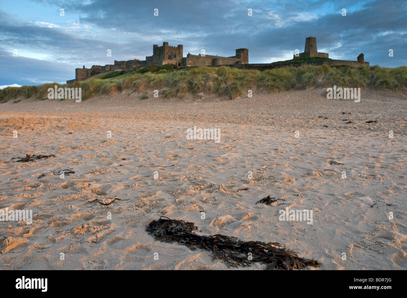 Il castello di Bamburgh dalla spiaggia prese al tramonto su una calda serata d'estate Foto Stock