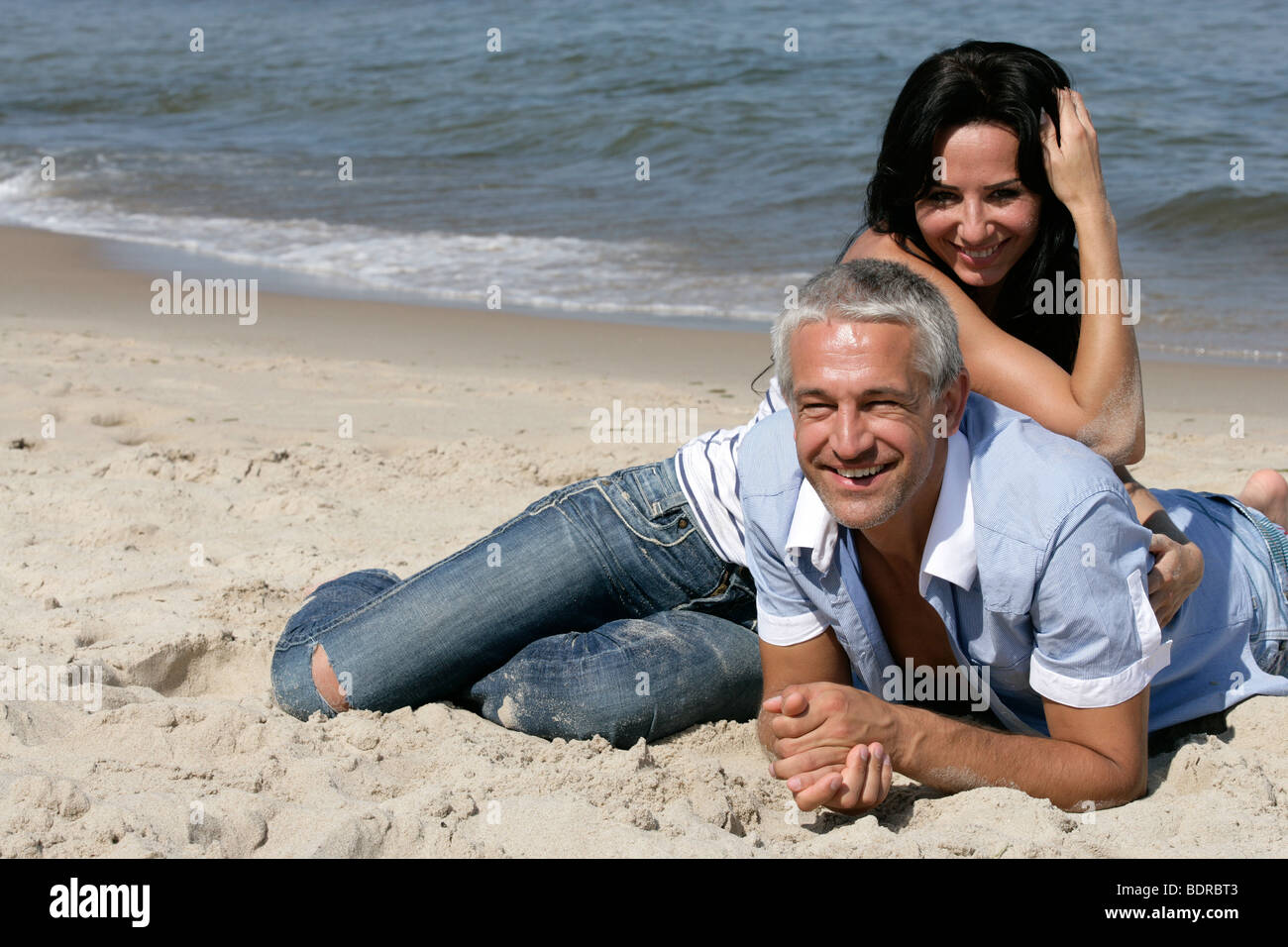 Felice Coppia di mezza età in appoggio sulla spiaggia, godendo le loro vacanze estive insieme. Foto Stock
