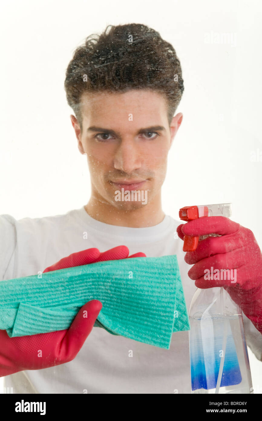 Junger Mann putzt mit eine Fensterscheibe mit Spr hflasche und Wischlappen Foto Stock