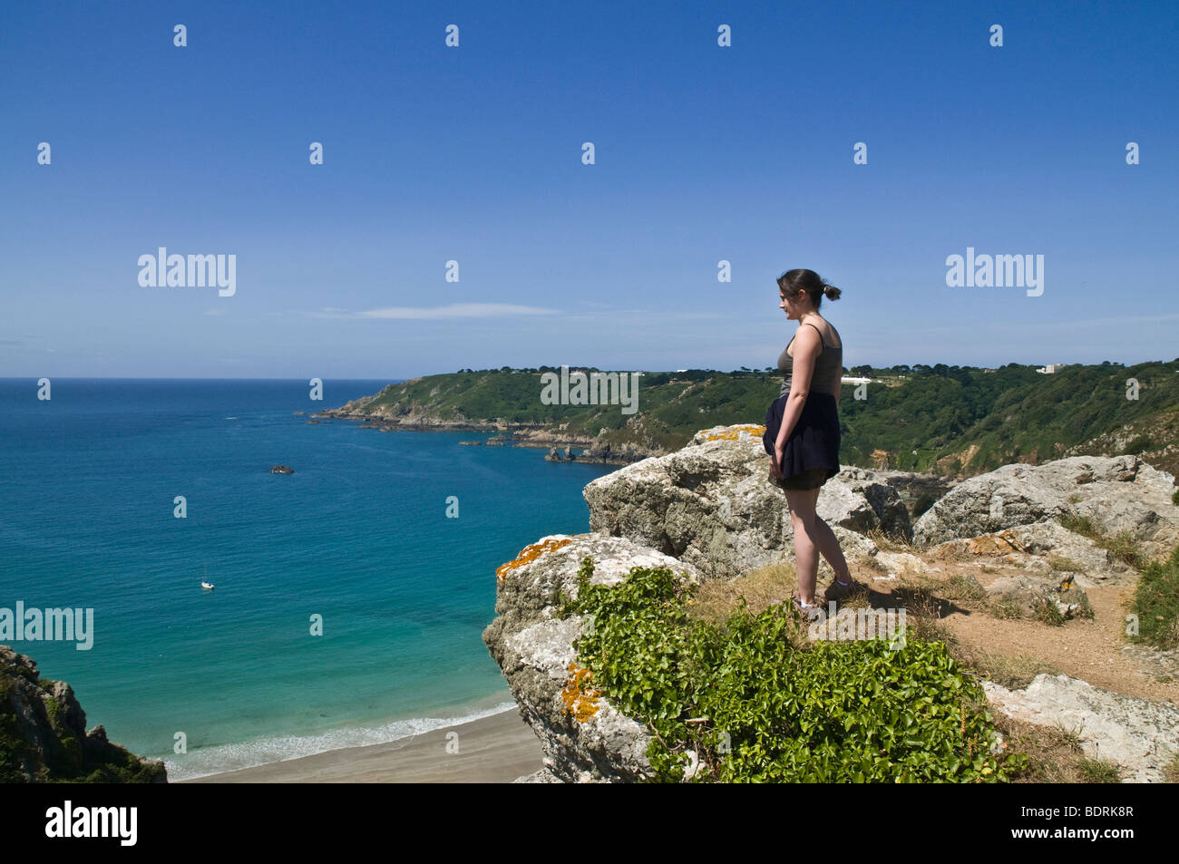 Dh Moulin Huet Bay St Martin Guernsey giovane donna che guarda la vista della baia e della costa meridionale viste persona ragazza walker Foto Stock