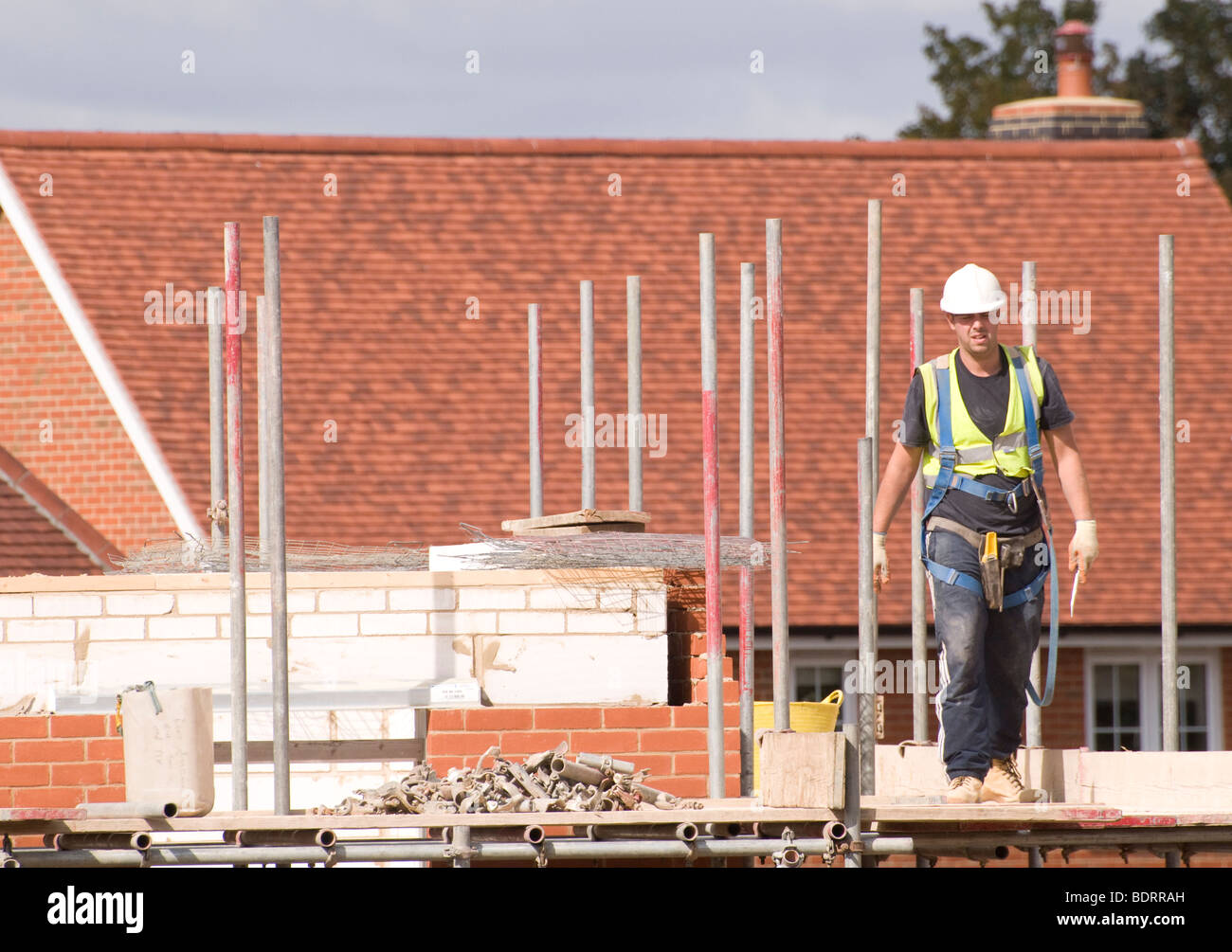 Un lavoratore edile camminando per ponteggi da una casa in costruzione. Foto Stock