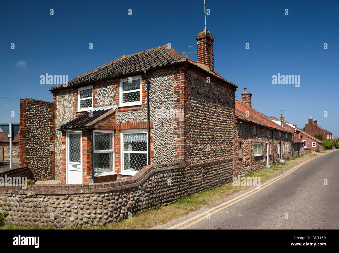 Regno Unito, Inghilterra, Norfolk, Paston, flint pebble cottage di fronte al fianco di vecchia terrazza di case basse Foto Stock