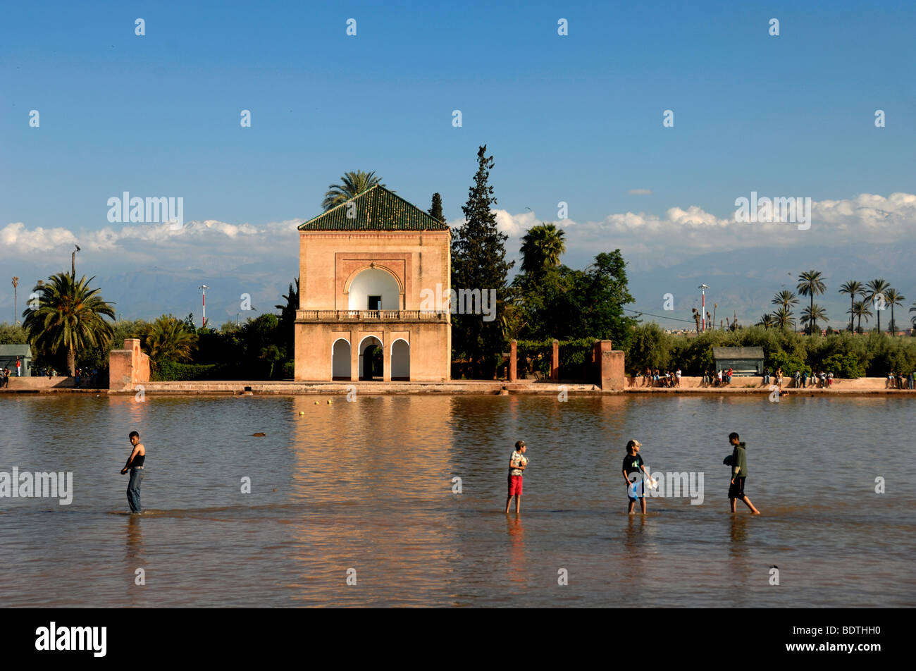 Ragazzi marocchini Wade attraverso il lago o la piscina di fronte la Menara Royal Pavilion di Giardini Menara marrakech marocco Foto Stock