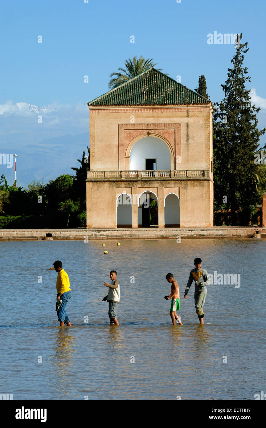 Ragazzi marocchini Wade attraverso il lago o la piscina di fronte la Menara Royal Pavilion di Giardini Menara marrakech marocco Foto Stock