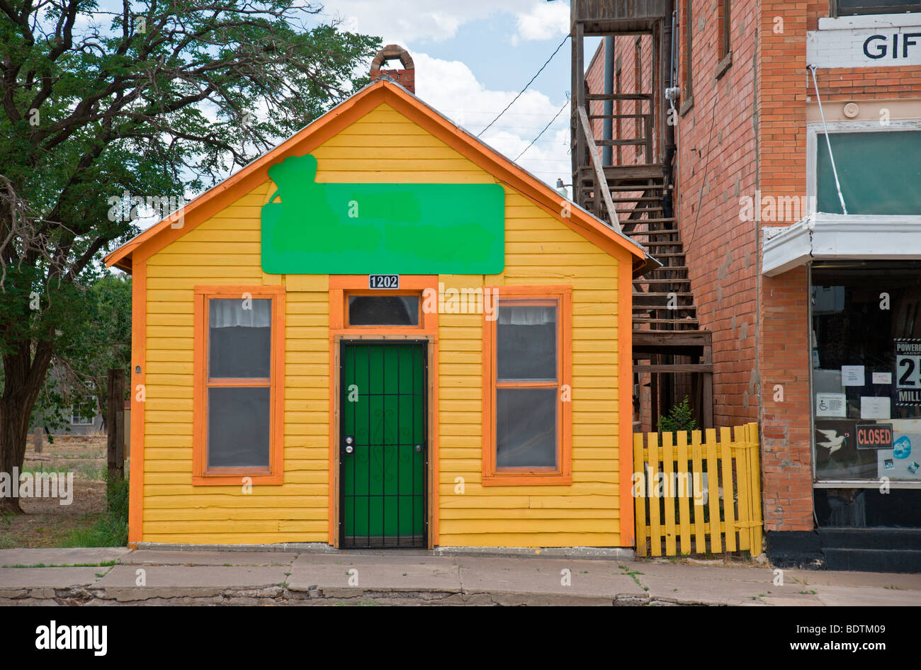 Una casa gialla con rivestimento arancione rifulge in Carrizozo, Nuovo Messico. Foto Stock