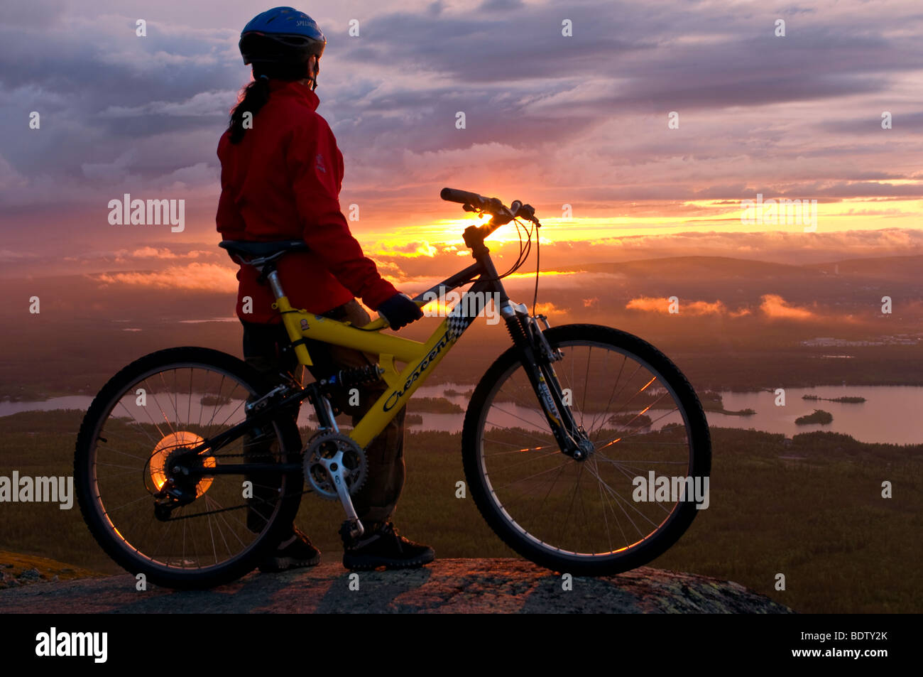 Femmina ciclista in discesa al sole di mezzanotte, Lapponia, Svezia Foto Stock