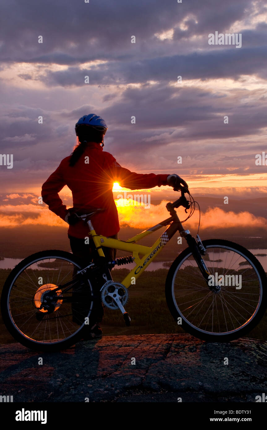 Femmina ciclista in discesa al sole di mezzanotte, Lapponia, Svezia Foto Stock