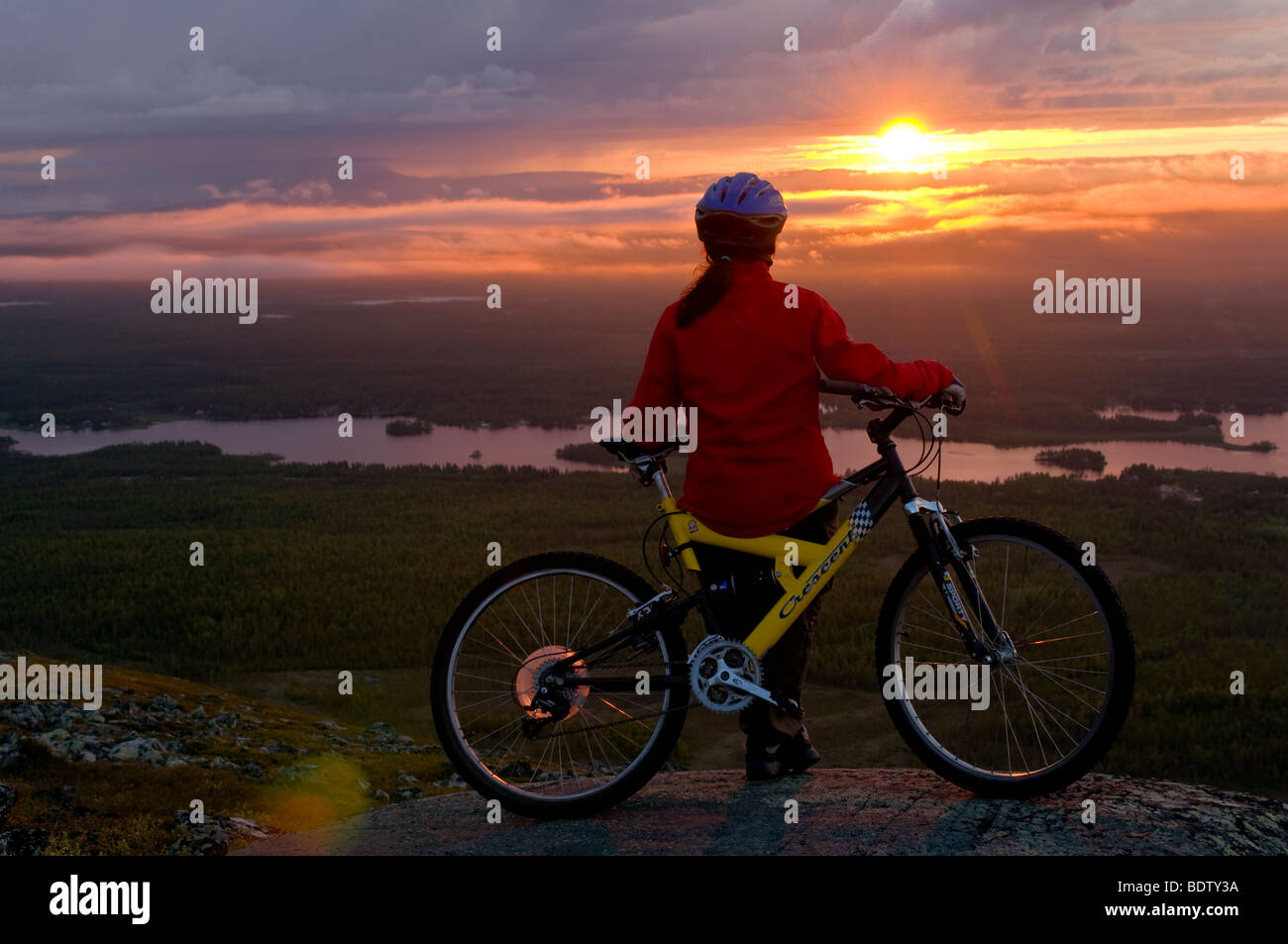 Femmina ciclista in discesa al sole di mezzanotte, Lapponia, Svezia Foto Stock