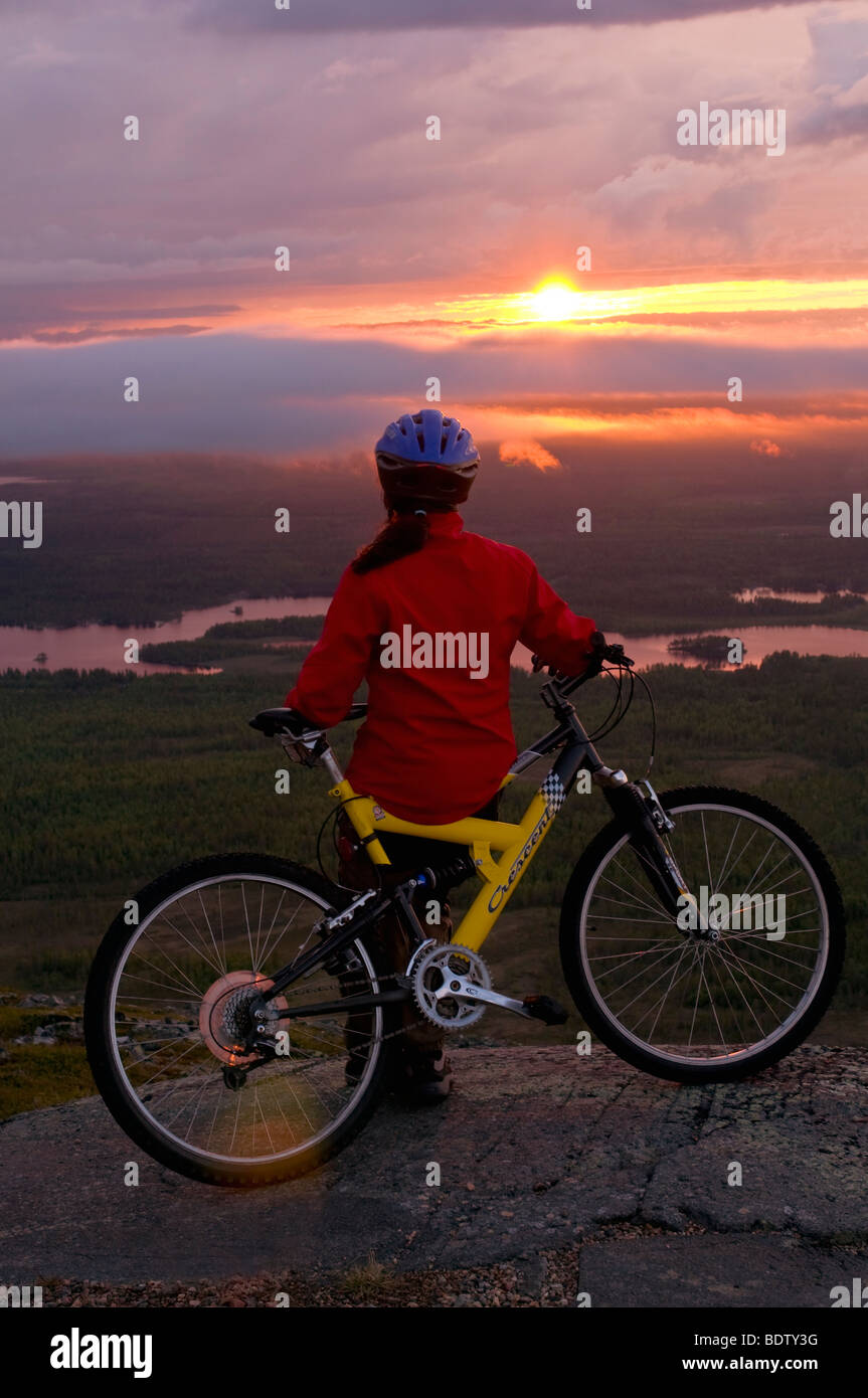 Femmina ciclista in discesa al sole di mezzanotte, Lapponia, Svezia Foto Stock