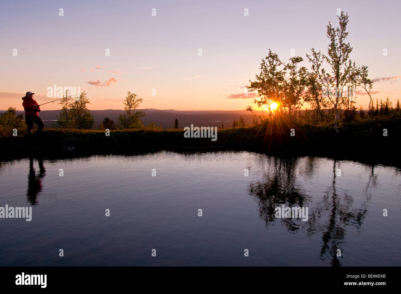 Pescatore femmina in corrispondenza di un lago di montagna in Lapponia al sole di mezzanotte, Svezia Foto Stock