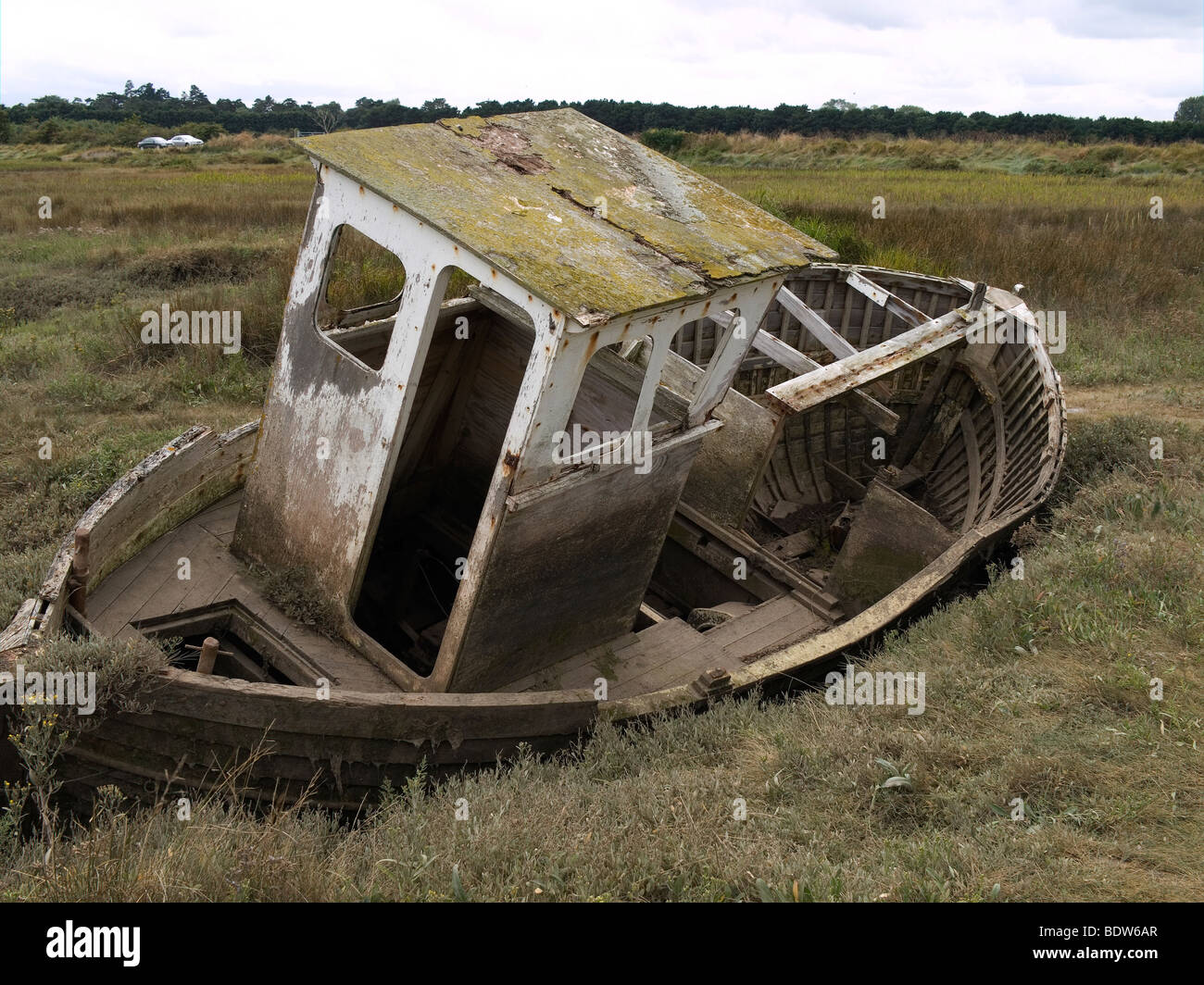 Un vecchio derelitti decadendo abbandonato la barca di legno su una palude salata a Thornham Norfolk Foto Stock