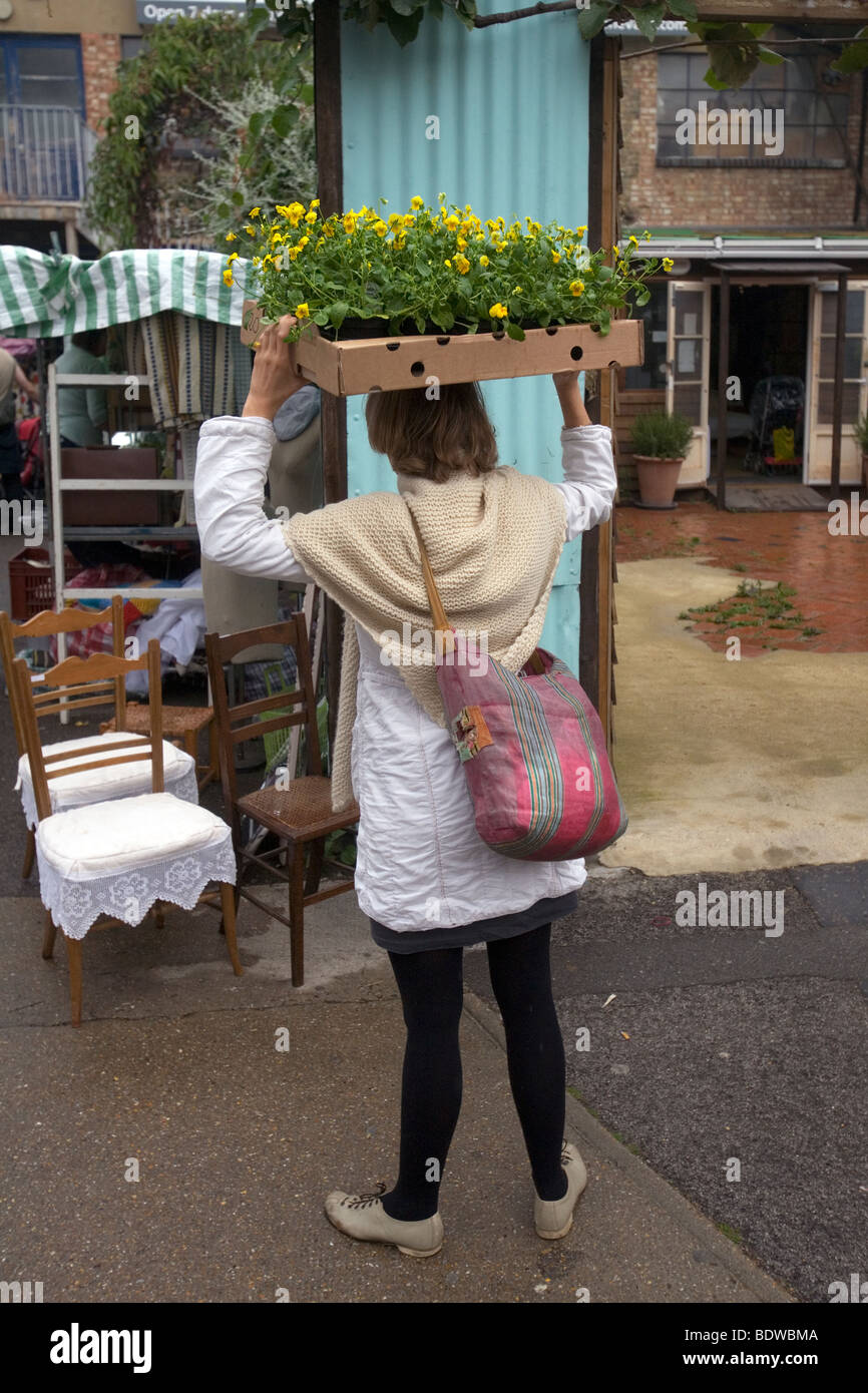 Una donna holding planst aloft vicino a Columbia road flower market nella zona est di Londra, Inghilterra Foto Stock