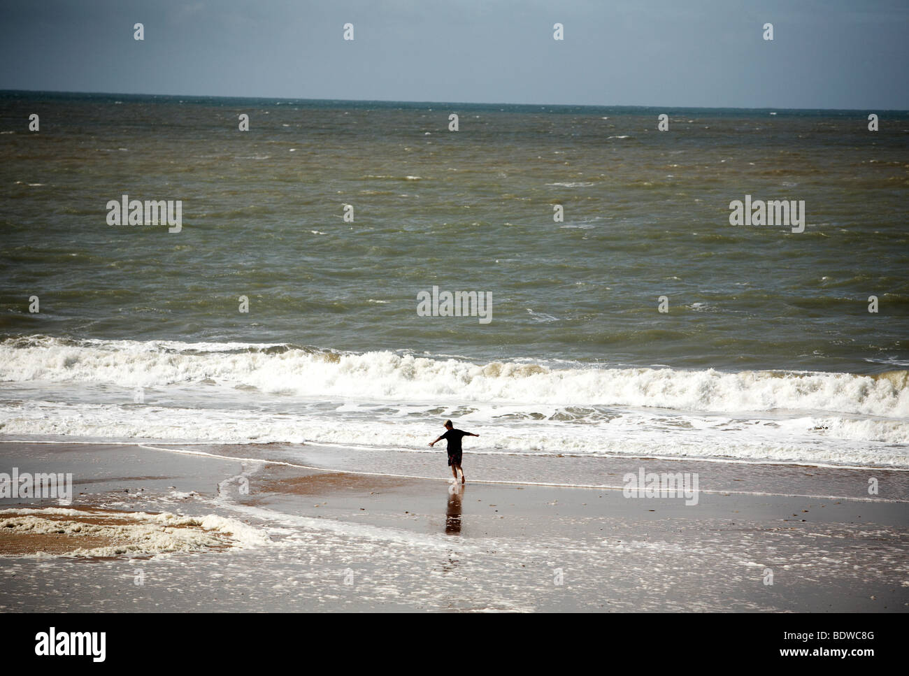 Una donna corre attraverso le onde con le braccia fuori in spiaggia a La Terriere in Vandea regione Foto Stock