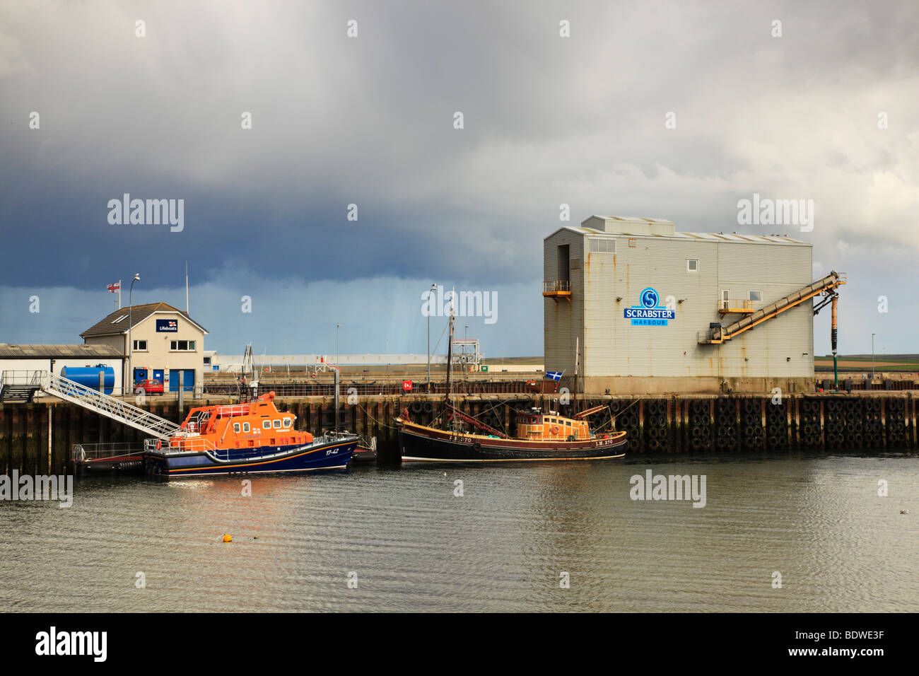 Porto di Scrabster con la scialuppa di salvataggio Severn Class, i Taylors e un antico peschereccio tradizionale a strascico sul molo. Thurso, Scozia Foto Stock