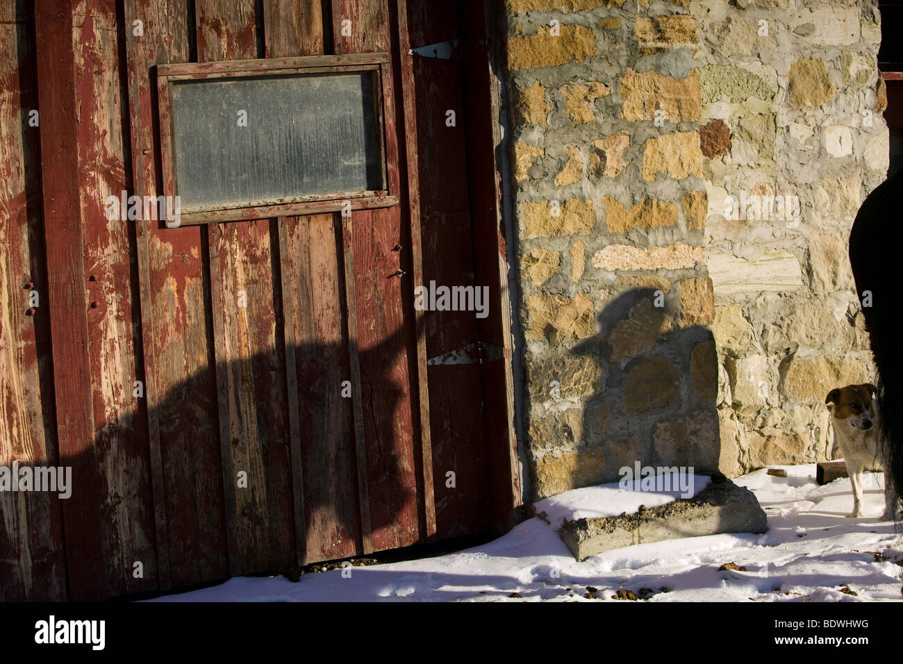 Caldo sole riflette da un vecchio ranch stone house la fusione della restante neve nel corral. Foto Stock