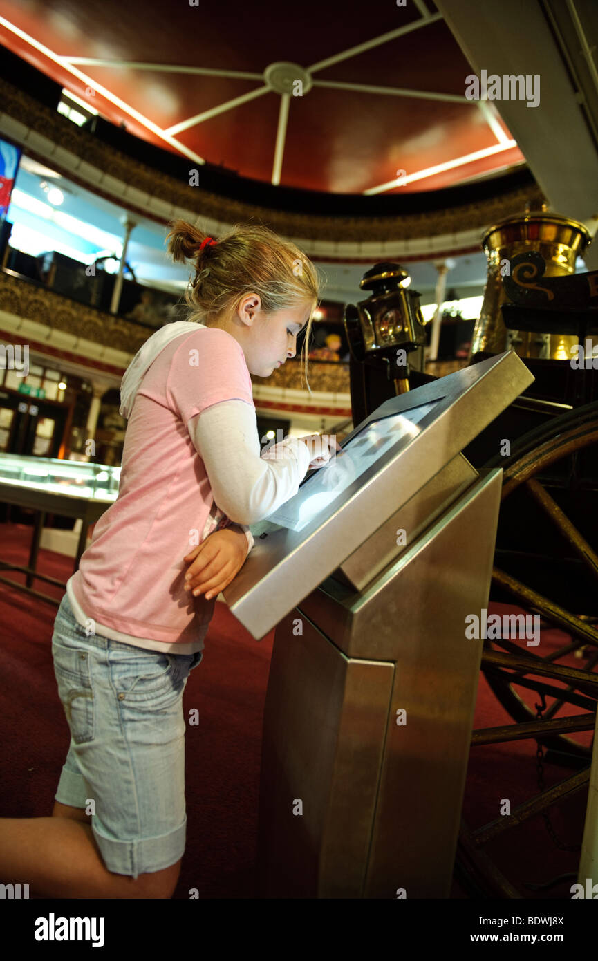 Una ragazza di 10 anni bambino utilizzando un pannello touch screen le informazioni del computer nel display Ceredigion Museum, Aberystwyth Wales UK Foto Stock