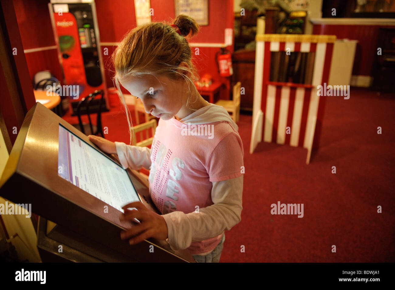 Una ragazza di 10 anni bambino utilizzando un pannello touch screen le informazioni del computer nel display Ceredigion Museum, Aberystwyth Wales UK Foto Stock