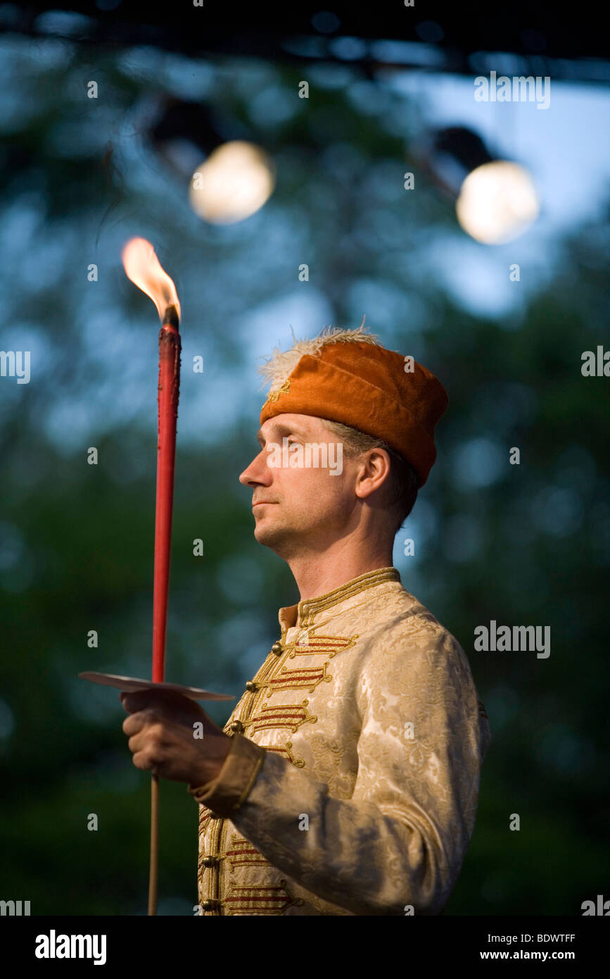 Un ballerino in piatti tradizionali ungheresi costumi folk detiene una torcia durante a prestazioni a un festival culturale a Pec, Ungheria Foto Stock