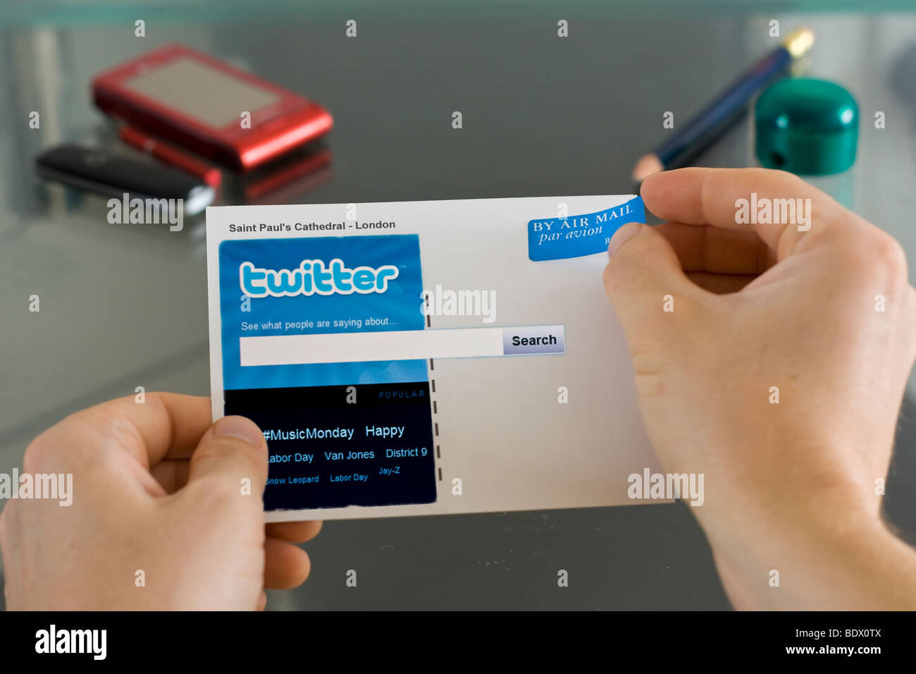 Un uomo mette un air mail un adesivo su una cartolina visualizzando il sito 'Twitter' Foto Stock