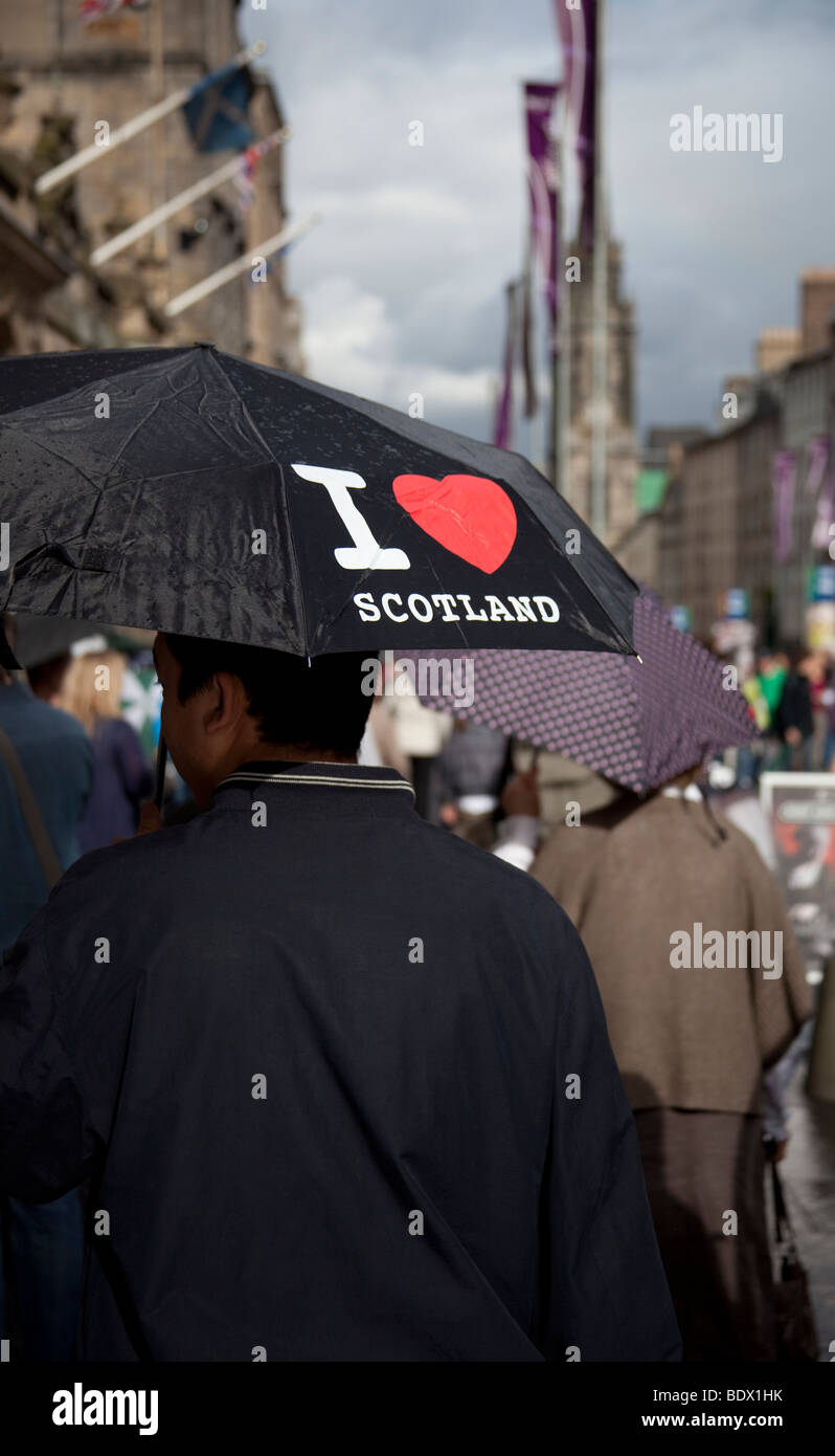 Uomo con ombrello sotto il sole e la pioggia con "Io amo la Scozia', Edinburgh, Regno Unito, Europa Foto Stock