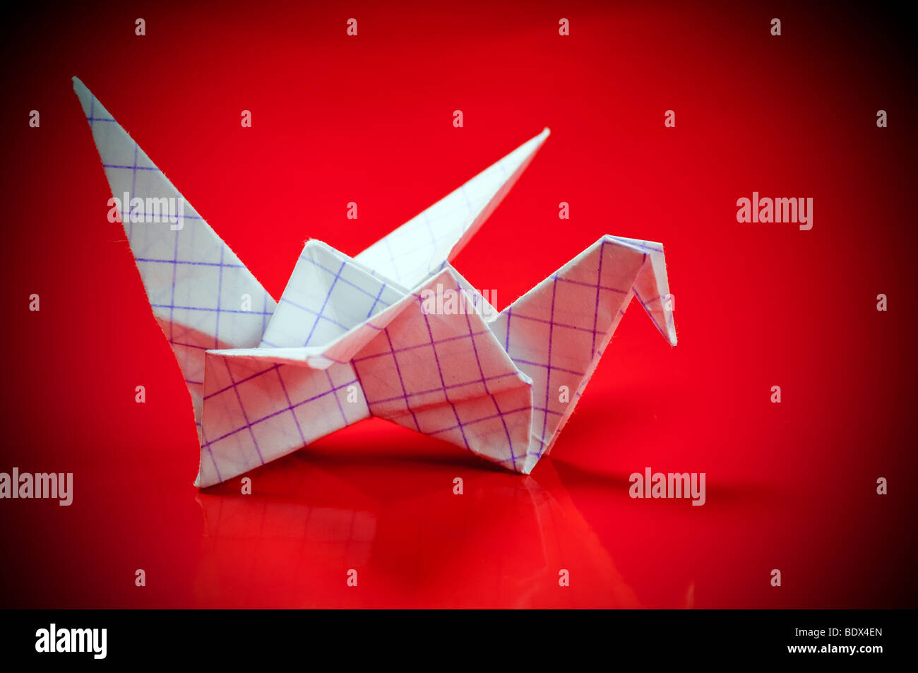 Una carta origami gru su sfondo rosso Foto Stock
