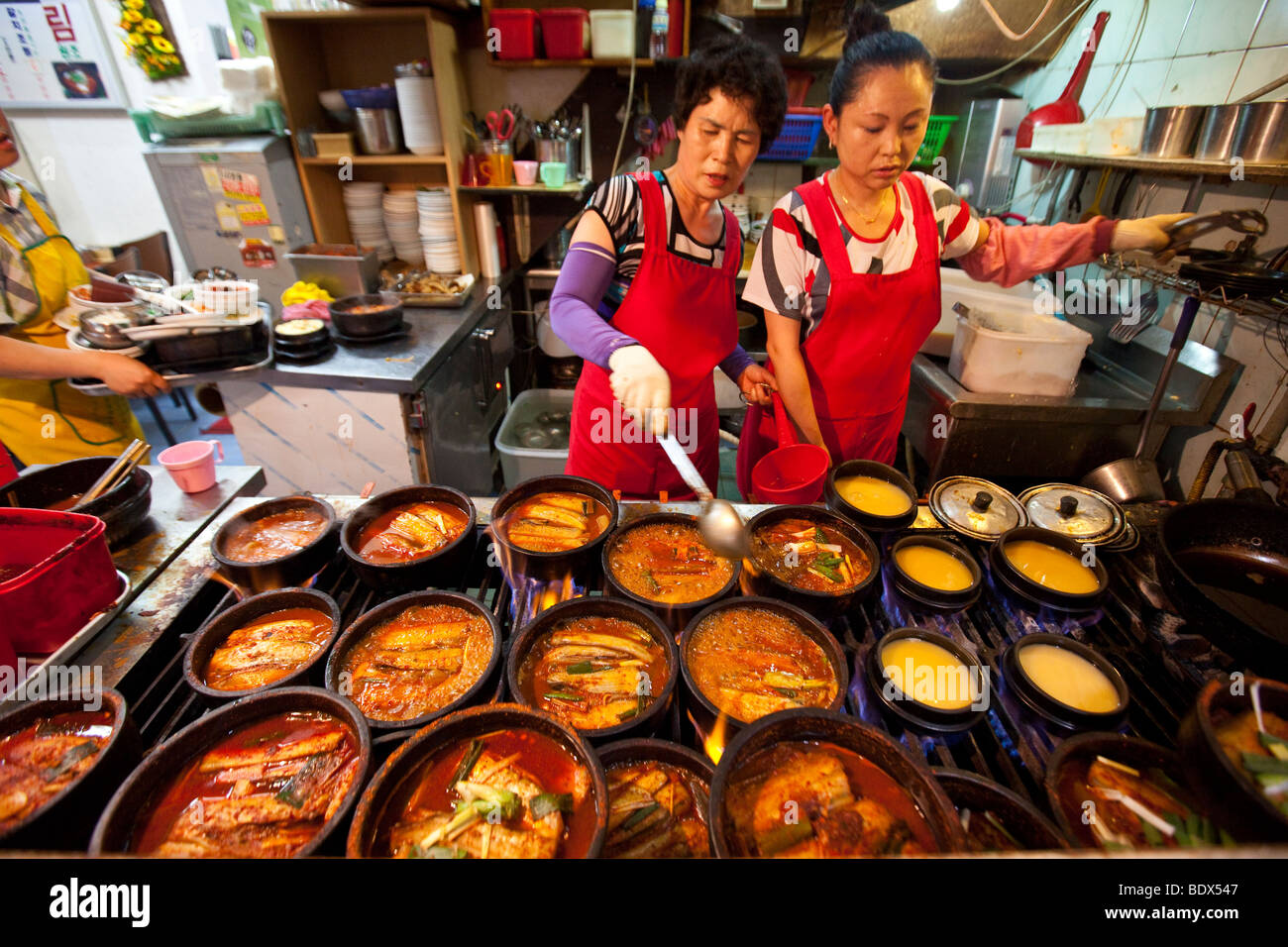 Donna di cottura jiggae piccante o stufato nel mercato Namdemun in Seoul COREA DEL SUD Foto Stock