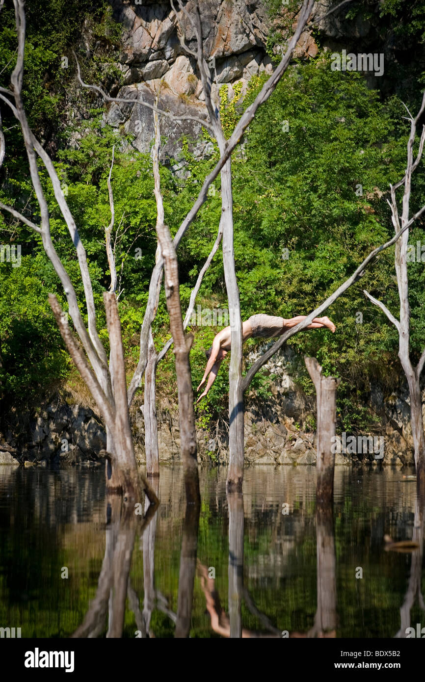 Un uomo tuffarsi nel fiume Sioule da un albero morto (Puy de Dôme - Francia). Homme plongeant dans une rivière depuis onu arbre. Foto Stock