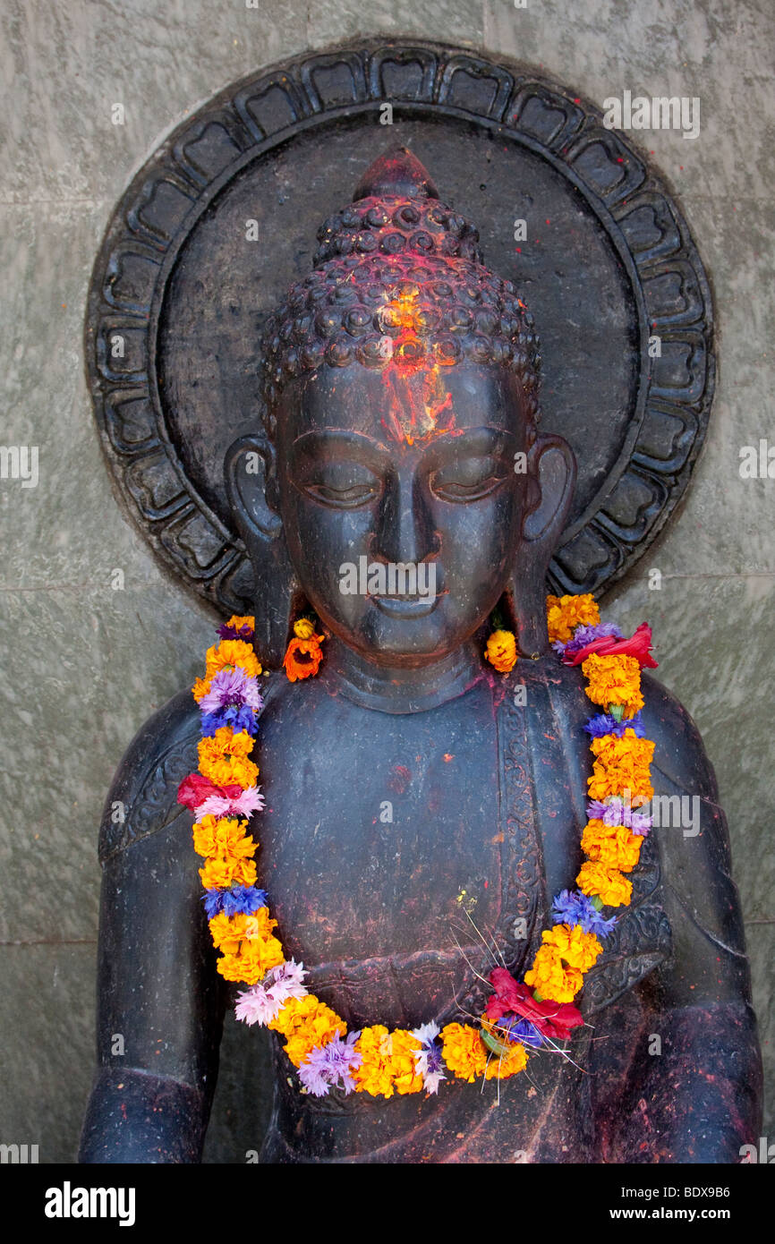 Kathmandu, Nepal. Statua del Buddha con una ghirlanda di fiori. Foto Stock