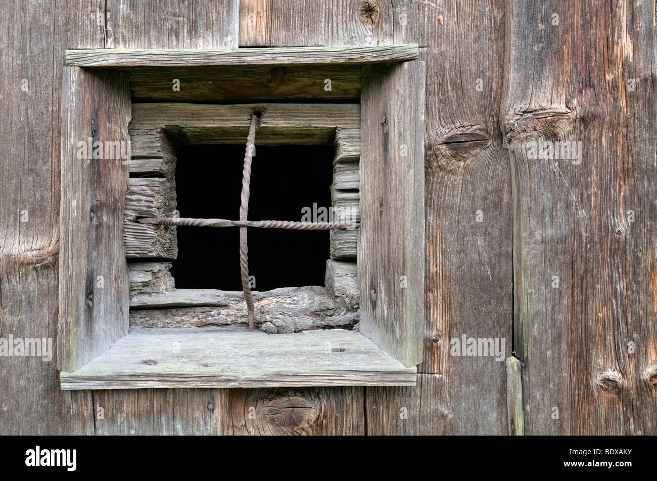 Finestra con barre di ferro in una parete in legno Foto Stock