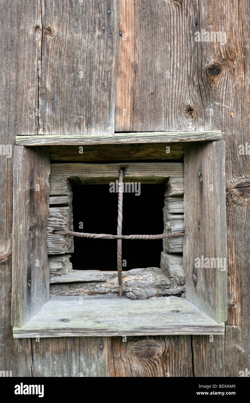 Finestra con barre di ferro in una parete in legno Foto Stock