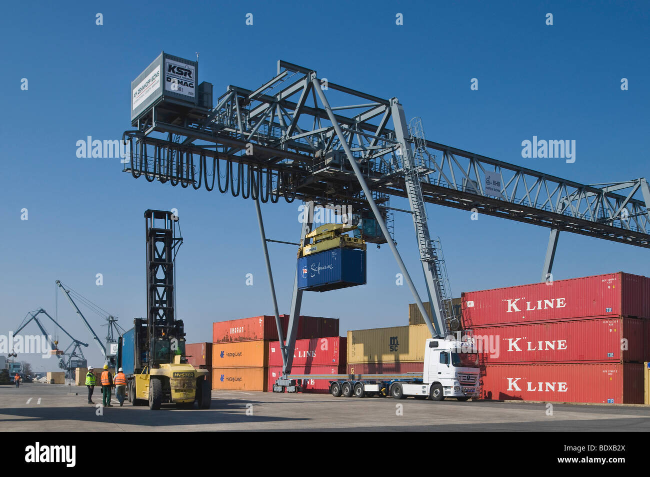 Terminale per container Bonn, gantry crane il caricamento di container su un camion, lavoratori in piedi accanto a un contenitore carrello al fron Foto Stock